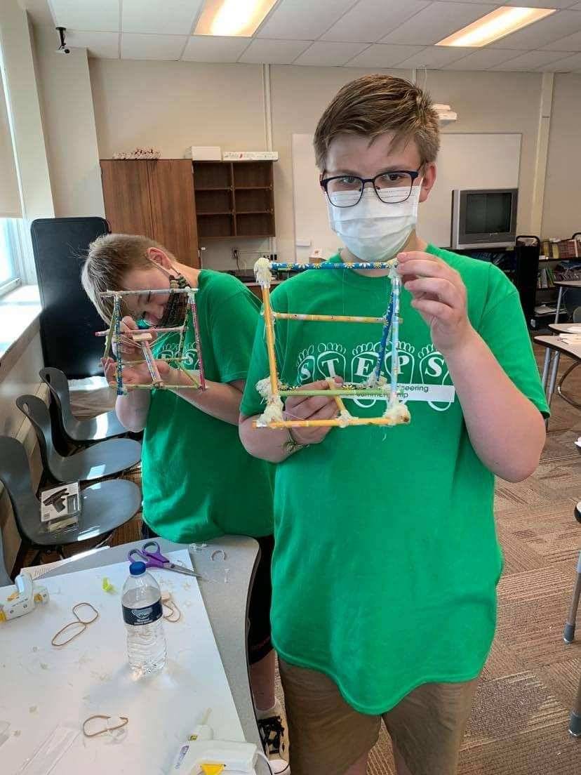 Two students show off their catapult projects